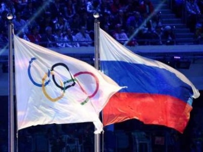 (FILES) This file photo taken on February 23, 2014 shows an Olympic Games flag and a Russian flag waving during the closing ceremony of the winter Olympics in Sotchi.